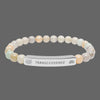 Beaded bracelet with a silver tag saying Transcendence with galaxy and lotus symbols