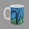 A white ceramic mug featuring an abstract art print with swirling blue and green paint with black script of word Awakening.