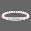 Beaded bracelet with a silver tag saying Transcendence with galaxy and lotus symbols