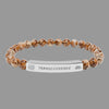 Beaded bracelet with a silver tag saying Transcendence with galaxy and lotus symbols