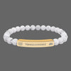 Beaded bracelet with a gold tone tag saying Transcendence with galaxy and lotus symbols